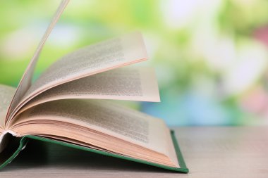 doğal zemin üzerine tahta masada açık kitap