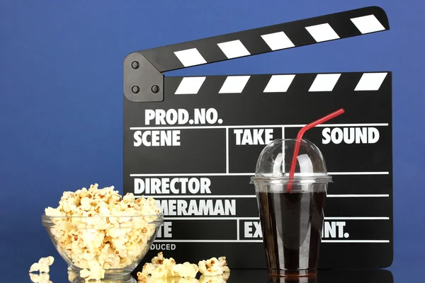 Film clapperboard, cola et pop-corn sur fond bleu — Photo