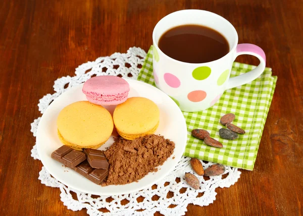 Cacao en taza con dulces y cacao en polvo en plato sobre mesa de madera —  Fotos de Stock