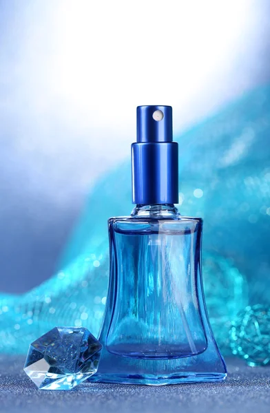 Perfume de mujer en hermosa botella sobre fondo azul — Foto de Stock