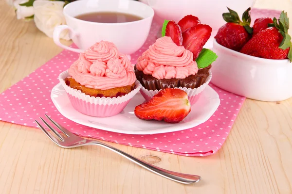 Hermosos cupcakes de fresa y té con sabor en la mesa de comedor de cerca —  Fotos de Stock