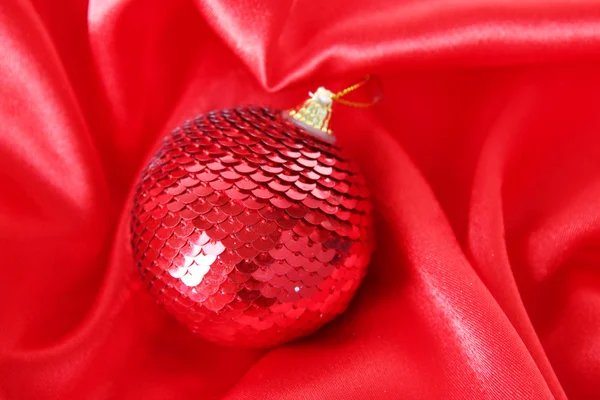 Bola de Natal bonita em pano de cetim vermelho — Fotografia de Stock