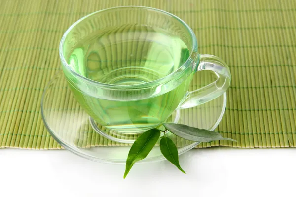 Genomskinlig kopp grönt te på bambu matta, isolerad på vit — Stockfoto