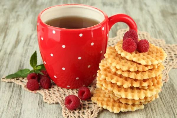 Cup of tea with cookies and raspberries on table close-up