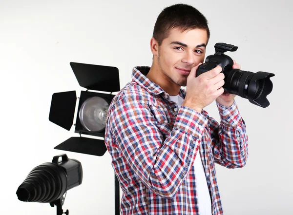 Fotógrafo guapo con cámara, sobre fondo de estudio fotográfico — Foto de Stock