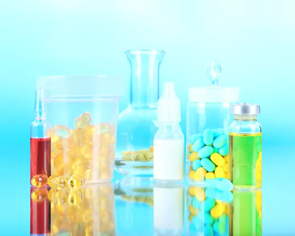 Medical bottles and pills on blue background — Stock Photo, Image