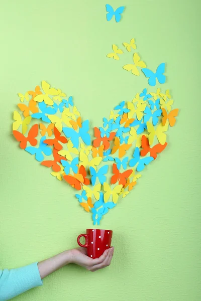 Mariposas de papel vuelan fuera de la taza sobre fondo de pared verde —  Fotos de Stock