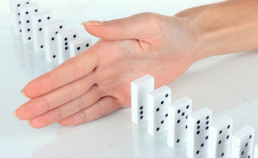 Hand stopping dominoes falling