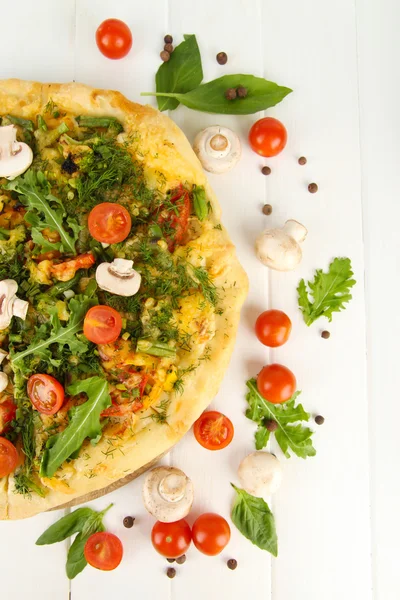 Smakelijke vegetarische pizza en groenten op houten tafel — Stockfoto