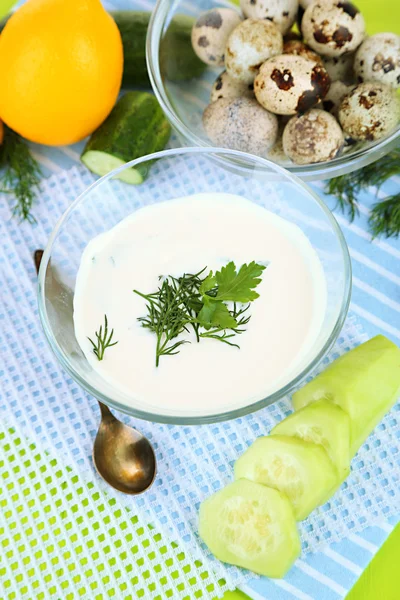 Yogurt al cetriolo in ciotola di vetro, su tovagliolo di colore, su sfondo di legno — Foto Stock