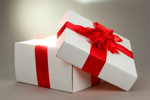 Geschenkbox mit hellem Licht auf grauem Hintergrund — Stockfoto