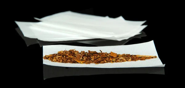 Tabaco e papel para enrolar, isolados a preto — Fotografia de Stock