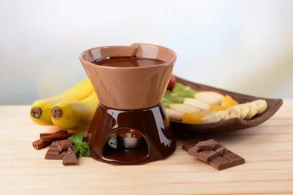 Chocolate fondue with fruits, on wooden table, on light background — Stock Photo, Image