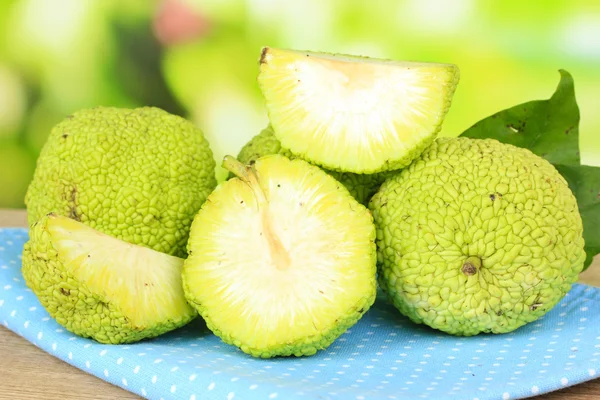 Осейдж Апельсиновые фрукты (Maclura pomifera) в корзине, на деревянном столе, на природе — стоковое фото