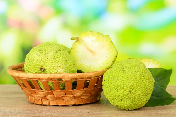 Osage orange frukter (maclura pomifera) i korg, på träbord, på natur bakgrund — Stockfoto