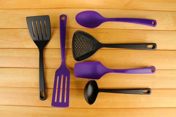 Plastic kitchen utensils on wooden background — Stock Photo, Image