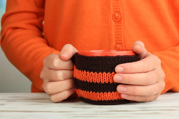 Cup with knitted thing on it in female hands close up — Stock Photo, Image
