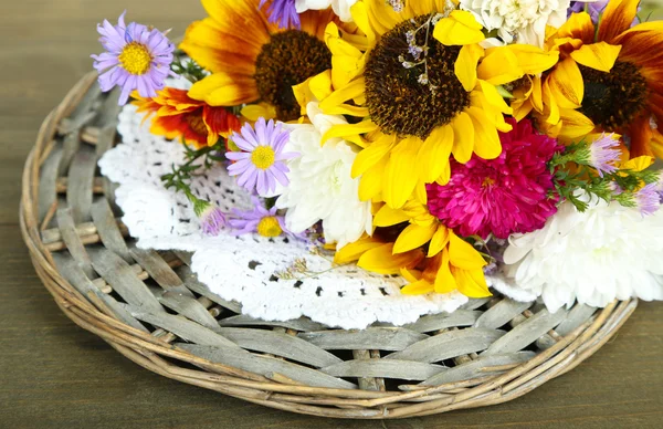 Bouquet of wild flowers on wicker tray on wooden background — Stock Photo, Image