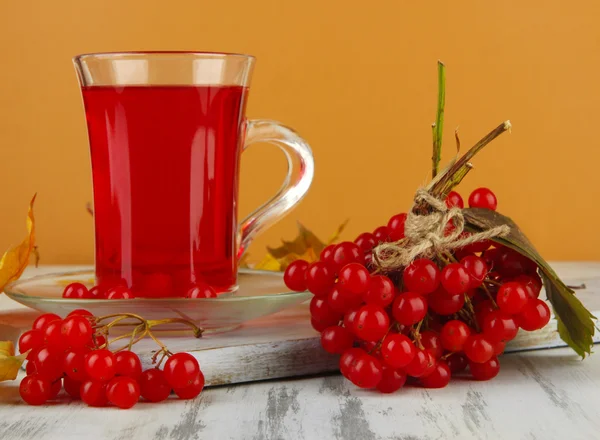 Red berries of viburnum and cup of tea on table on beige background — Stock Photo, Image