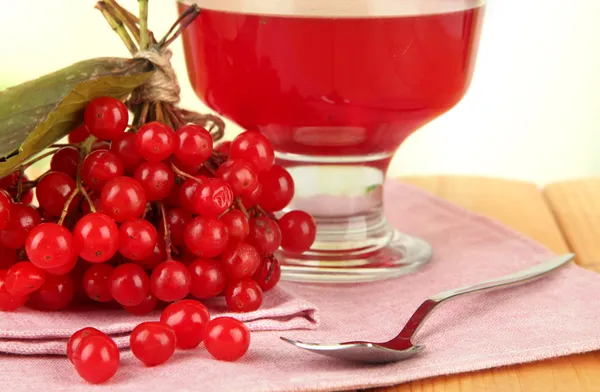 Red berries of viburnum and bowl with jam on table on bright background — Stock Photo, Image