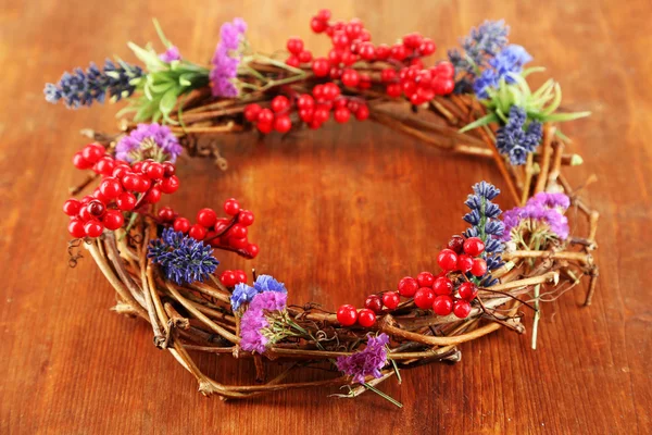 Corona de ramas secas con flores y viburnum en la mesa de madera de cerca —  Fotos de Stock