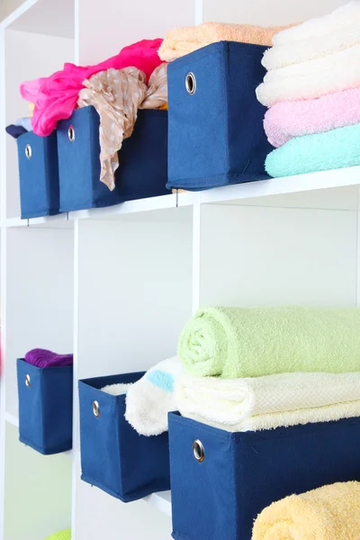 Blue textile boxes with towels and clothes in white shelves — Stock Photo, Image