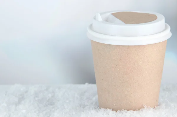 Hot drink in paper cup with snow on bright background — Stock Photo, Image