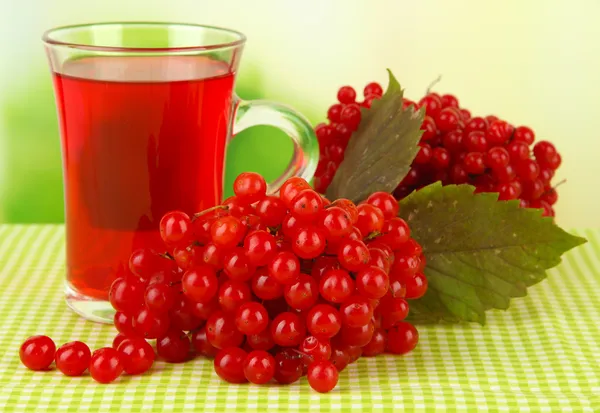 Red berries of viburnum and cup of tea on tablecloth on bright background — Stock Photo, Image