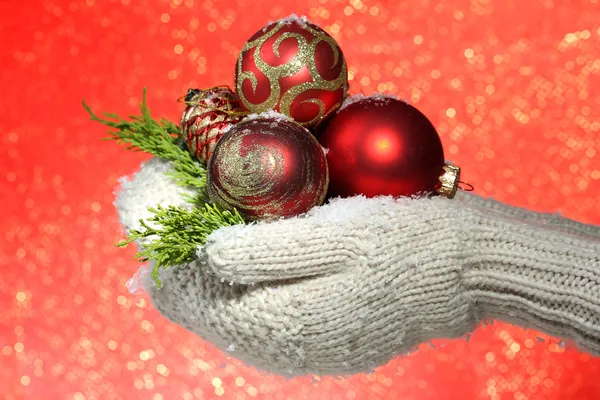 Female hands in mittens Christmas tree balls, on color background — Stock Photo, Image