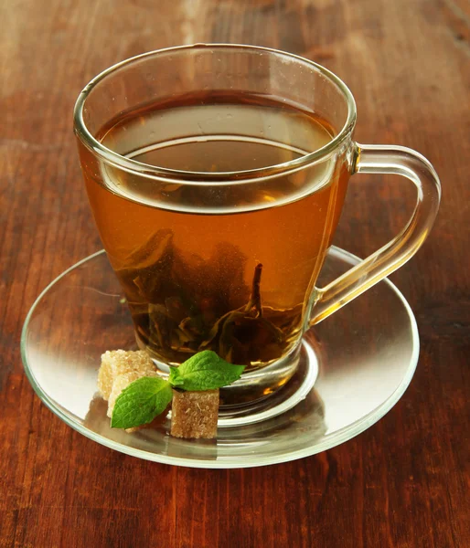 Xícara transparente de chá verde com açúcar no fundo de madeira — Fotografia de Stock