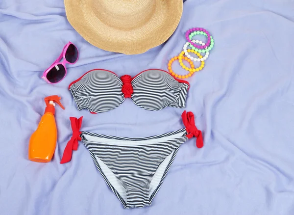 Badeanzug und Strandartikel auf lila Hintergrund — Stockfoto