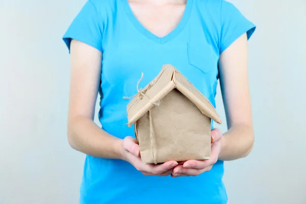 Frauenhände halten ein Haus in braunes Kraftpapier gewickelt — Stockfoto