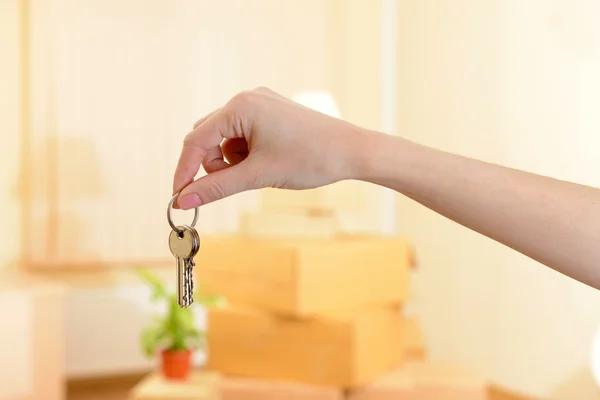 Mão feminina com teclas ob pilha de caixas de fundo: conceito de casa em movimento — Fotografia de Stock