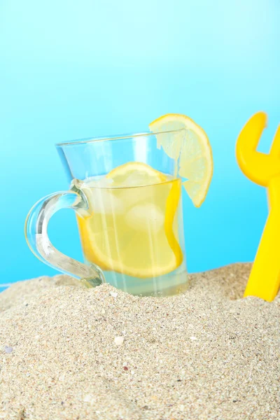 Cold tea in sand on blue background — Stock Photo, Image