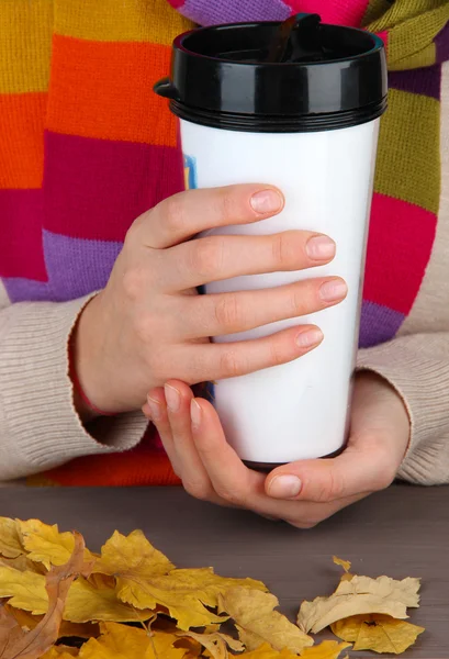 Hot drink in plastic glass in hands on wooden table close up — Stock Photo, Image