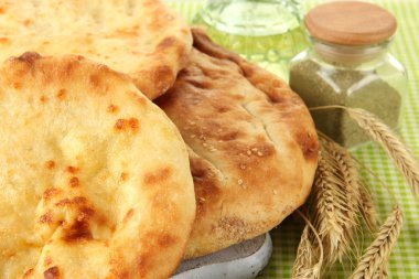 Pita ekmekler baharatlar ile ahşap stand ve sivri masa örtüsü üzerinde kapat