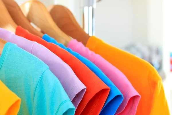 Variety of casual t-shirts on wooden hangers — Stock Photo, Image