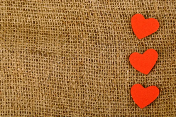 Hearts made of felt on sacking background — Stock Photo, Image