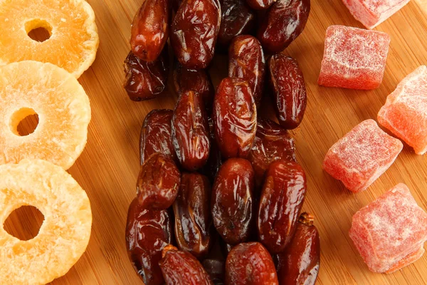 Dried dates with candied pineapples and Turkish delights on wooden background — Stock Photo, Image