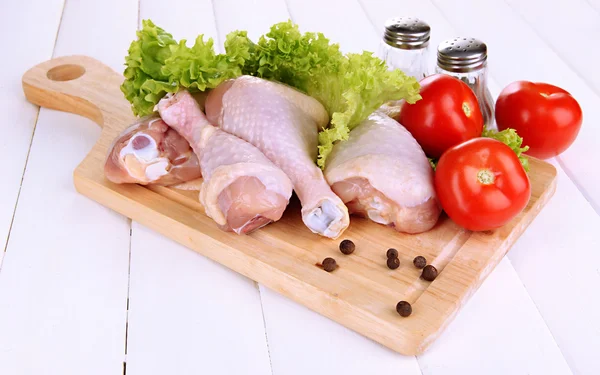 Pernas de frango cru na tábua de madeira de perto — Fotografia de Stock