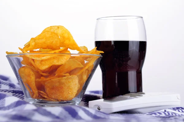 Chips in bowl, cola and TV remote on plaid isolated on white — Stock Photo, Image