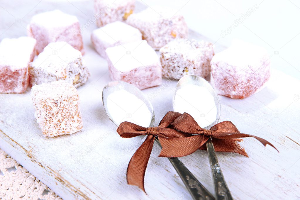 Tasty oriental sweets (Turkish delight) with powdered sugar, on wooden desk