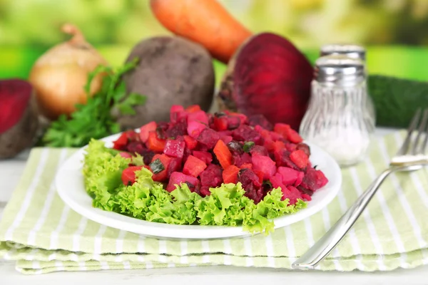 Beet salad on plate on napkin on wooden table on nature background — Stock Photo, Image