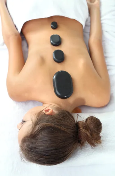 Beautiful young woman having stone massage in spa salon — Stock Photo, Image