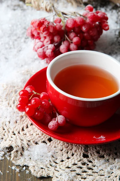 Stilleven met planten van viburnum thee in cup, bessen en sneeuw, op houten achtergrond — Stok fotoğraf