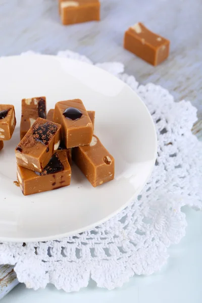 Many toffee on plate on cutting board isolated on white — Stock Photo, Image