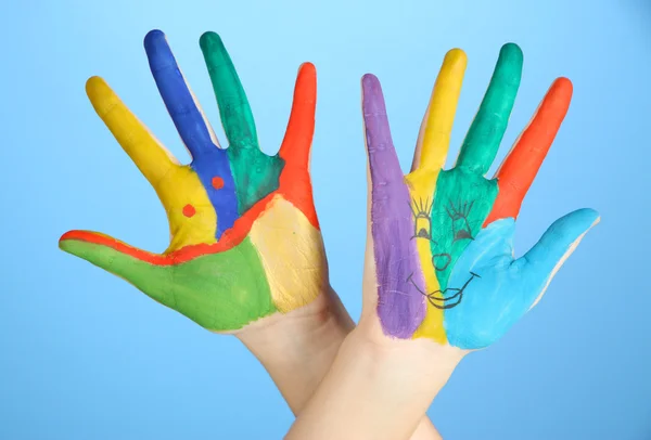 Mãos pintadas com sorriso no fundo azul — Fotografia de Stock