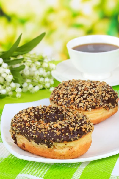 Sweet donuts with cup of tea on table on bright background — Stock Photo, Image