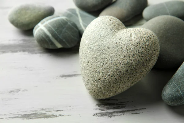 Grey stone in shape of heart, on color wooden background — Stock Photo, Image