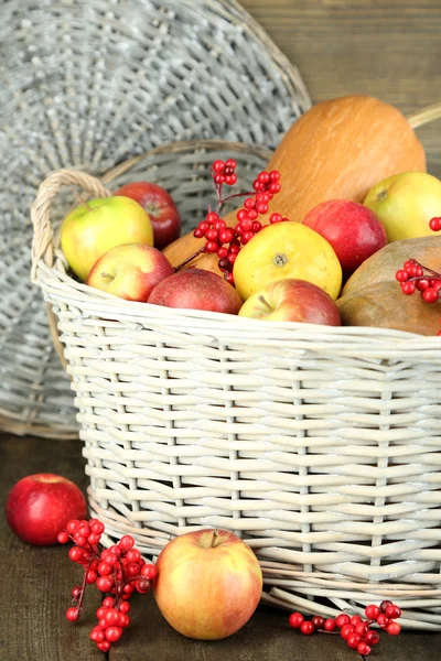 Saftige Äpfel und Kürbis im Holzkorb auf dem Tisch in Großaufnahme — Stockfoto